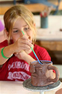 Child glazing camp pottery mug