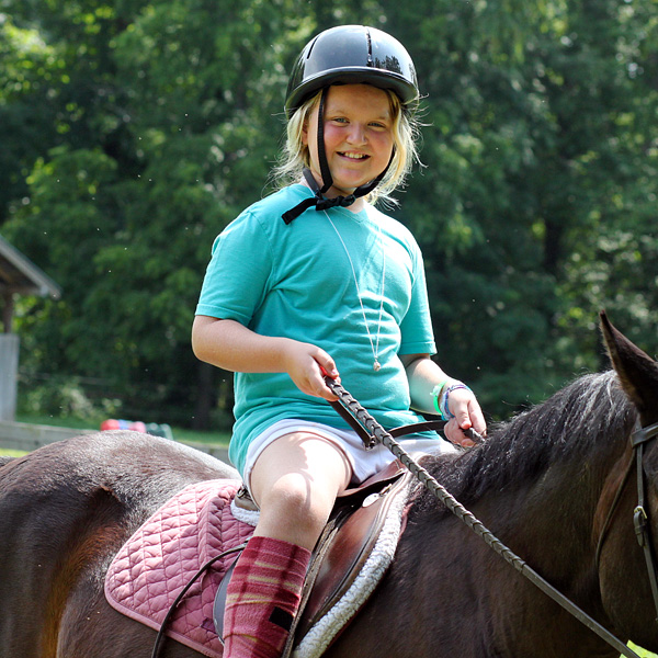 Young camper kid horseback riding