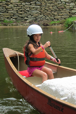 Young camper girl learning to canoe