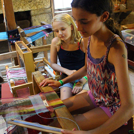Camp girls weaving on floor loom