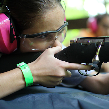Girl aiming a rifle at summer camp
