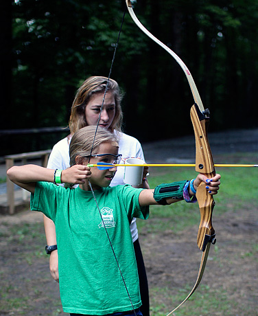 Camp girls having archery instruction