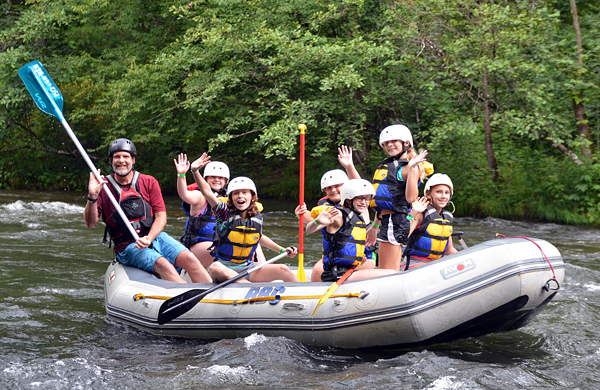 Girls waving while in whitewater rafting boat