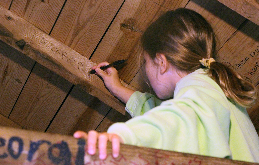 Girl writing her name inside camp cabin