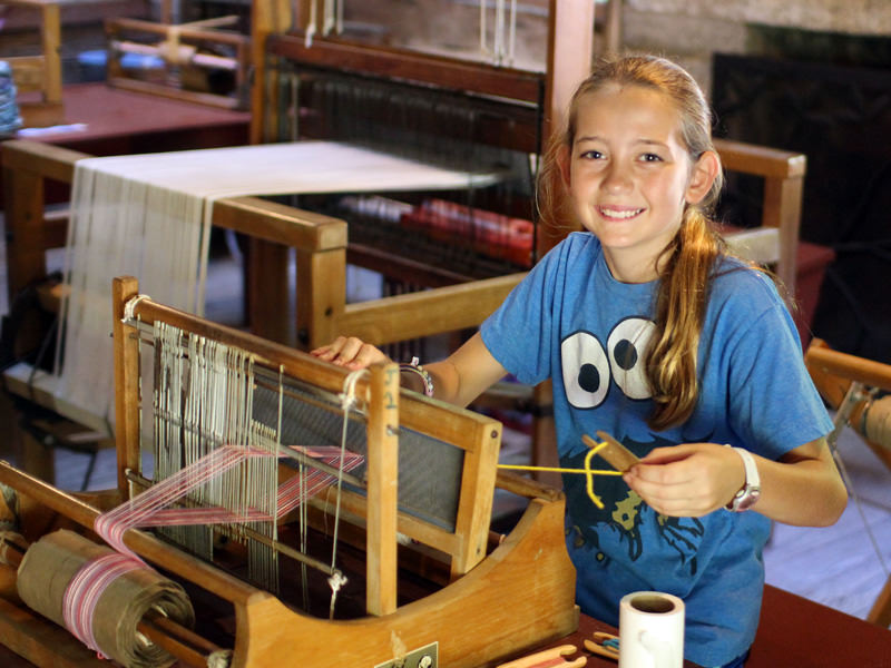 Camp girl using table loom for weaving