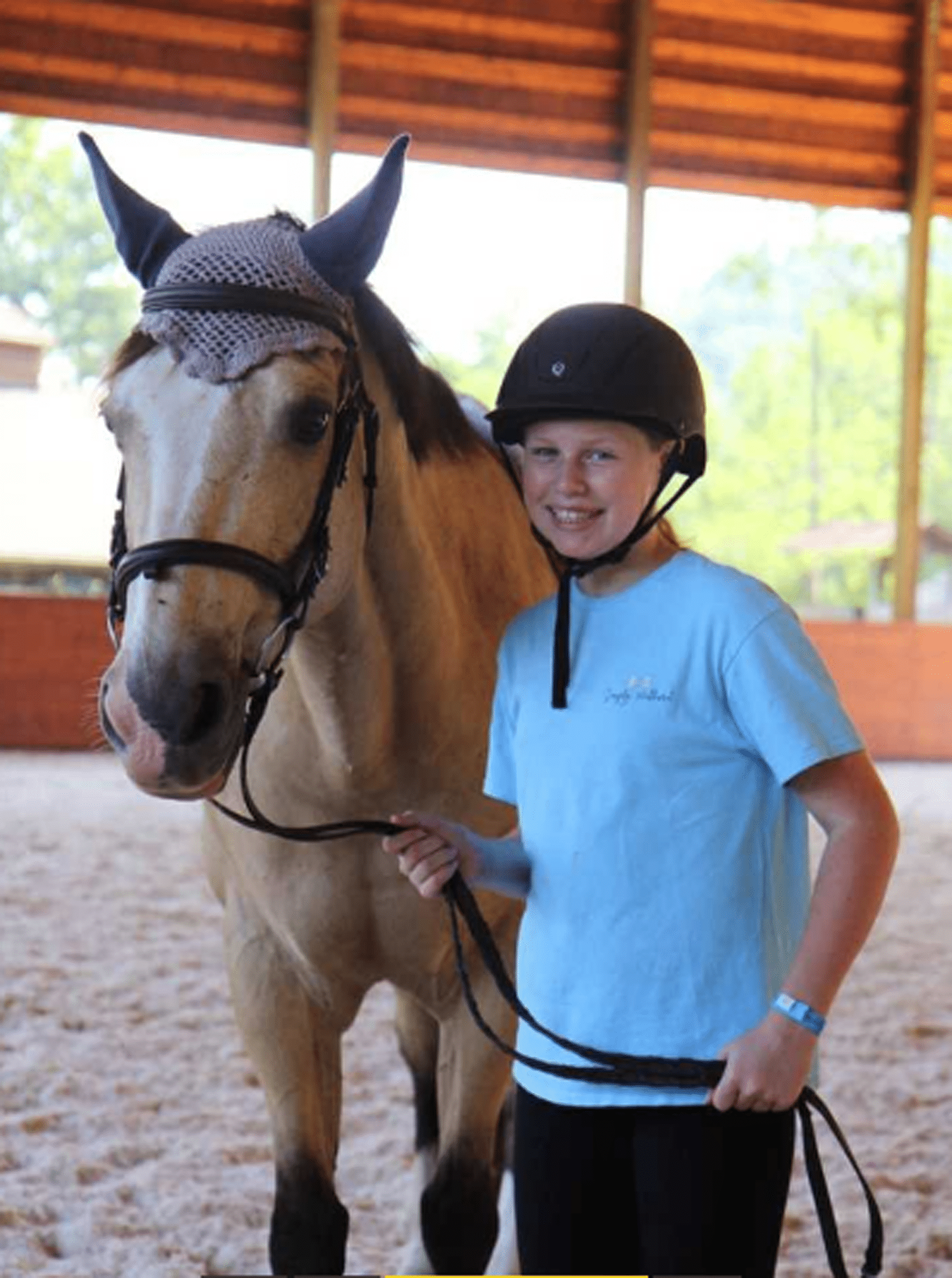 buckskin horse and girl wearing helmet and blue shirt