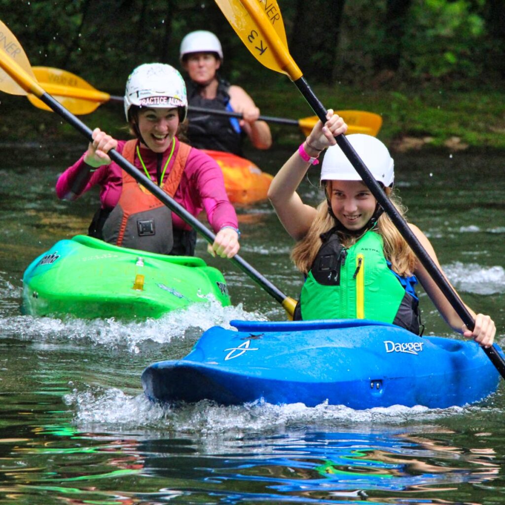 camp girl and staff member racing in kayaks