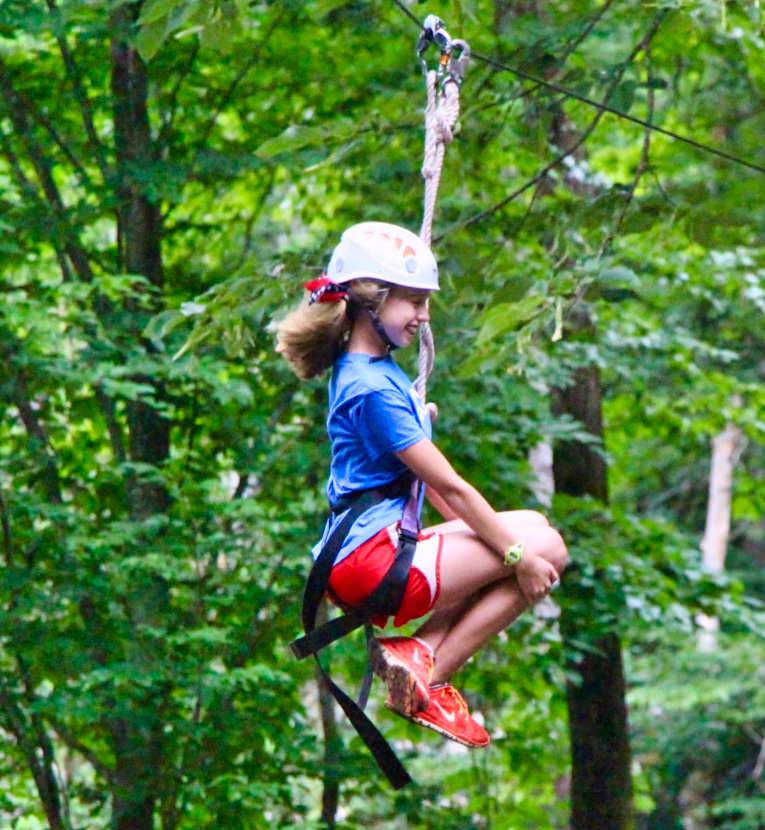 teen girl riding zipline at camp