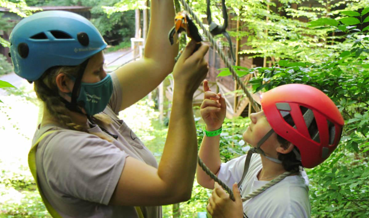 Camp adventure staff woman helping child