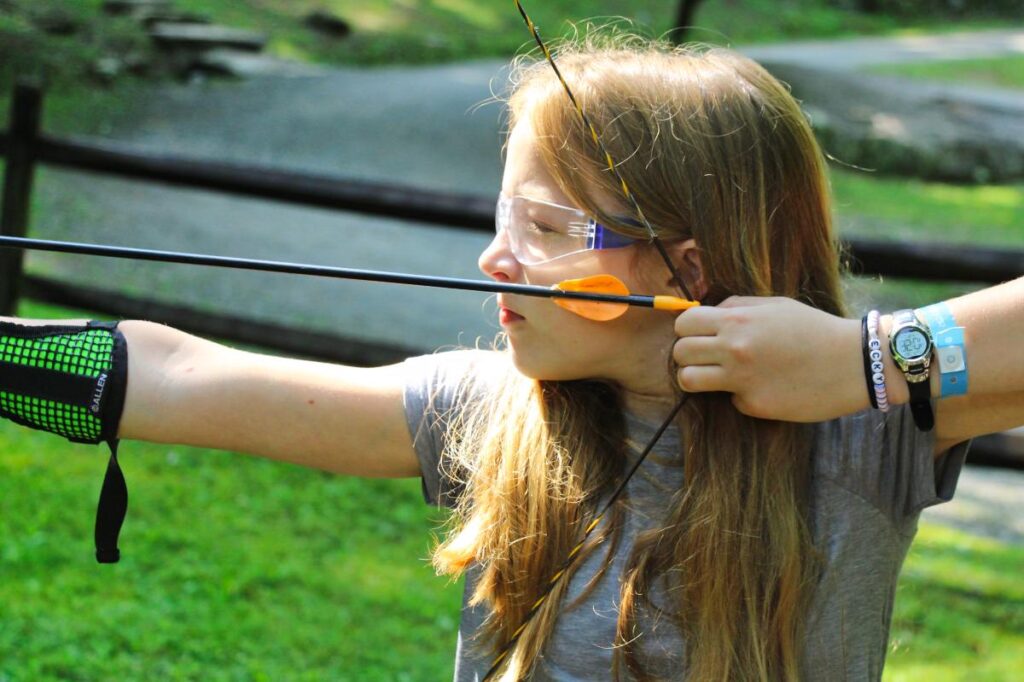child pulling back archery bow