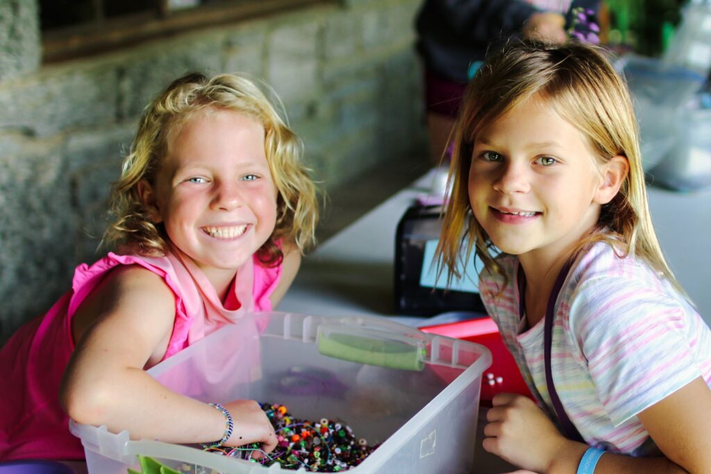 two girls with tub of bracelet beads