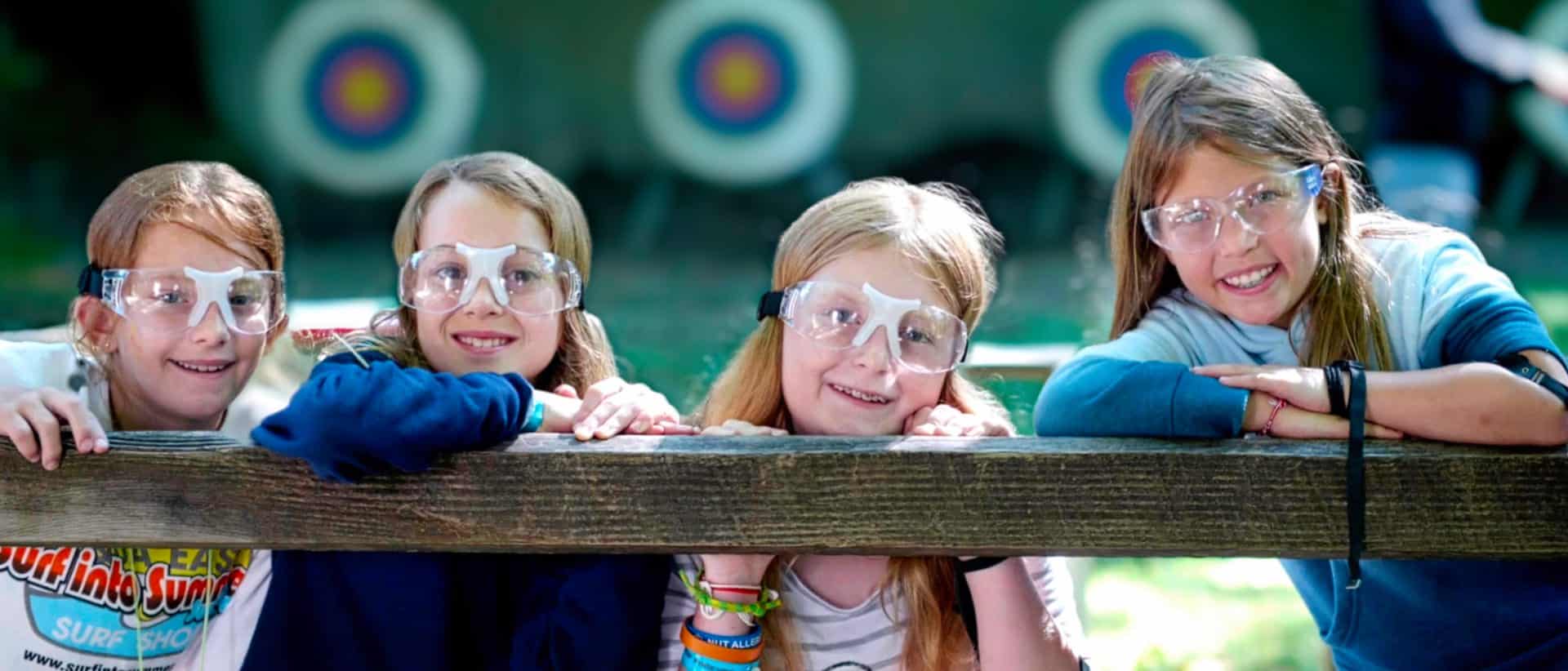 four camp girls wearing archery goggles
