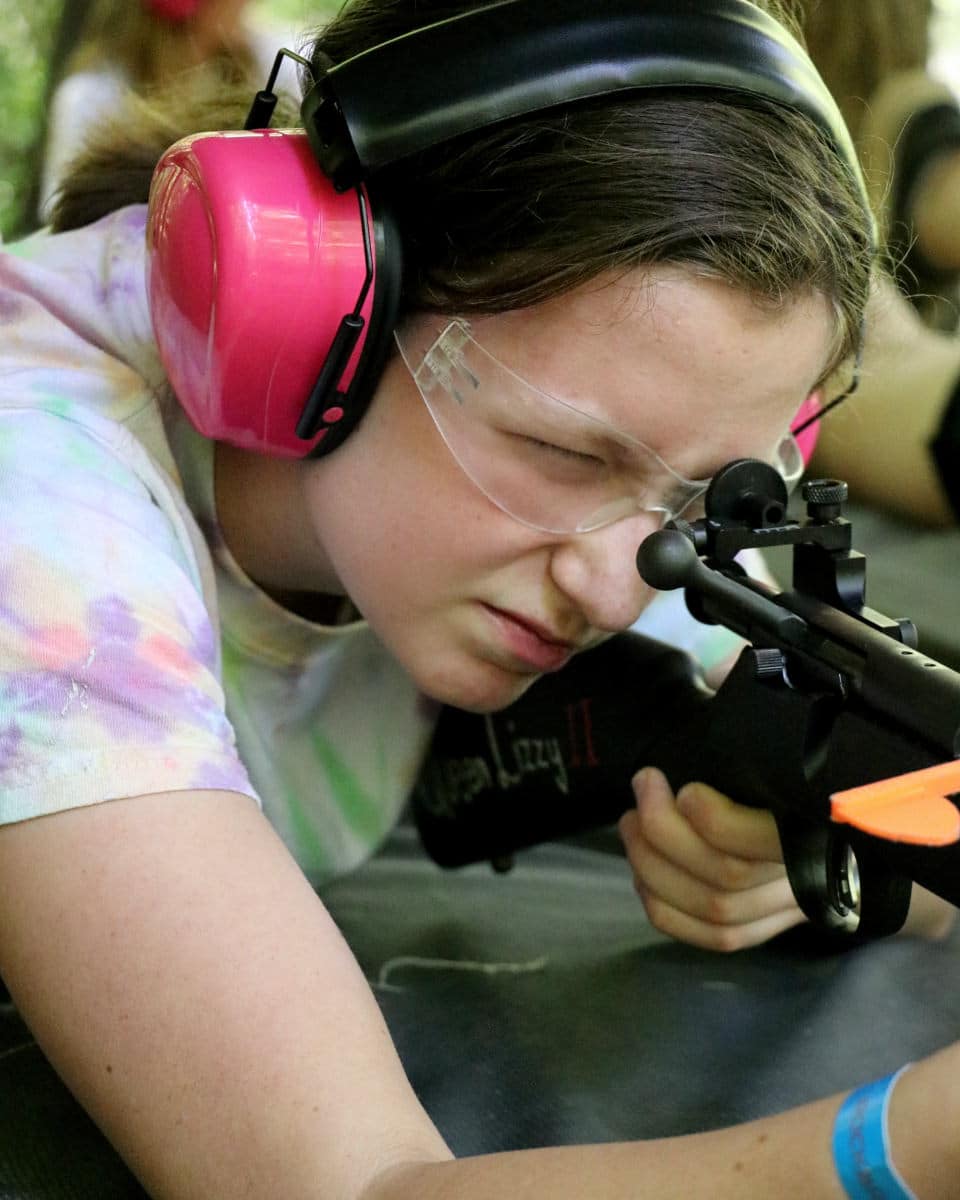summer camp girl aiming a rifle